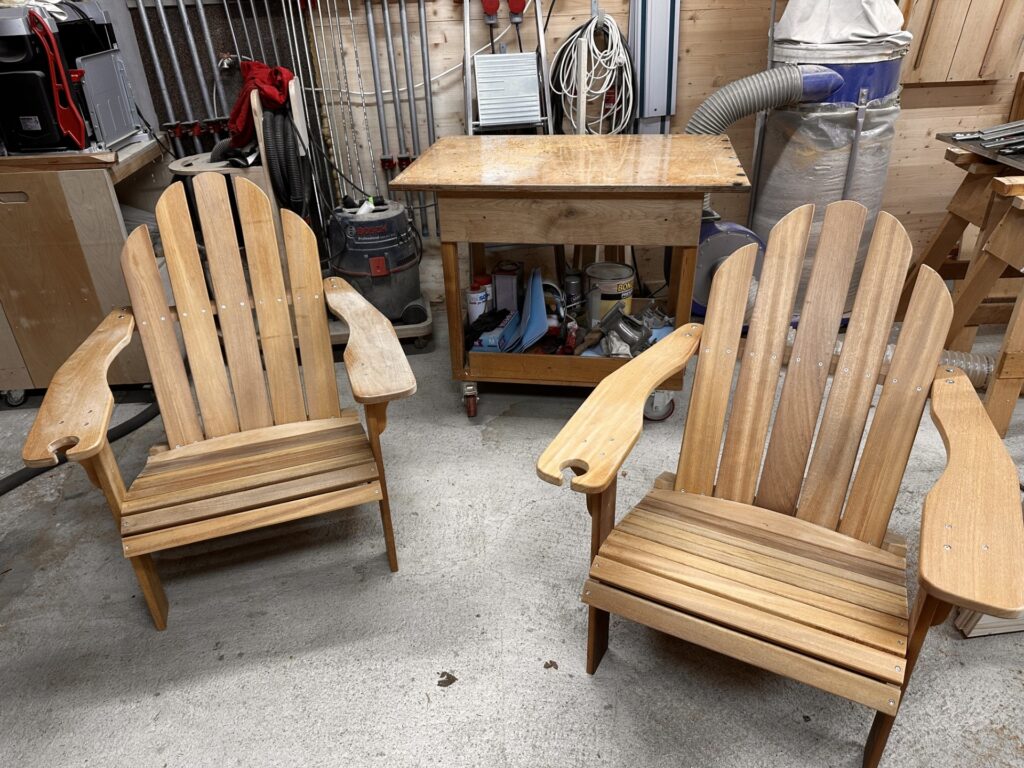 Zwei fertig montierte Adirondack-Stühle in der Holzwerkstatt.