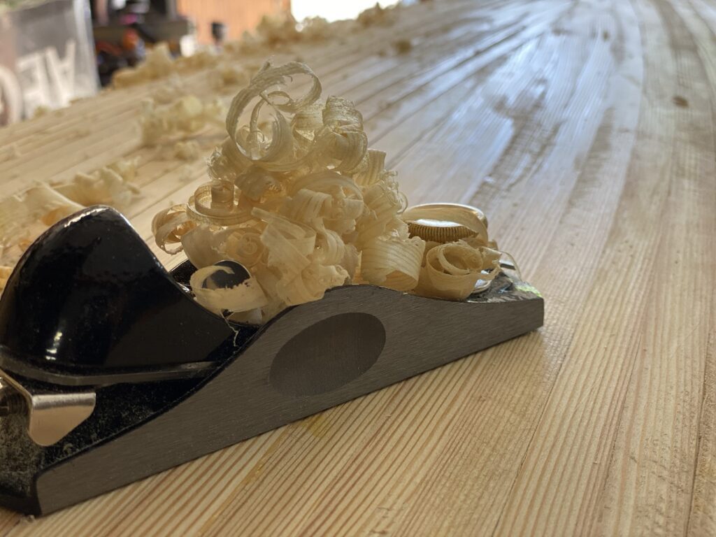 Handhobel und Holzspäne auf dem Leistenrumpf des Kanus.