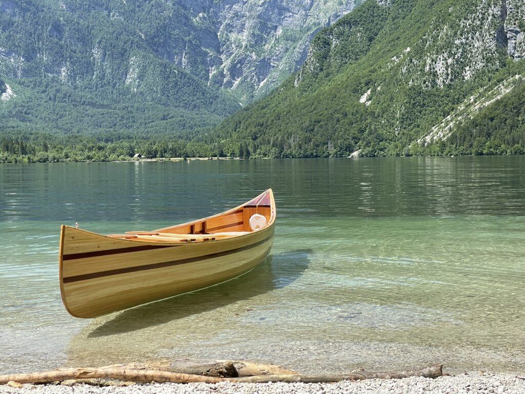 Schrägansicht des Holzkanus im klaren Wasser nahe dem Ufer.